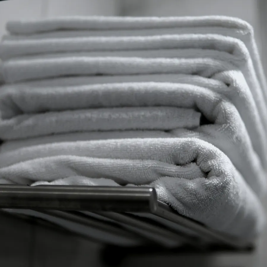 Folded white towels stacked on a rail.